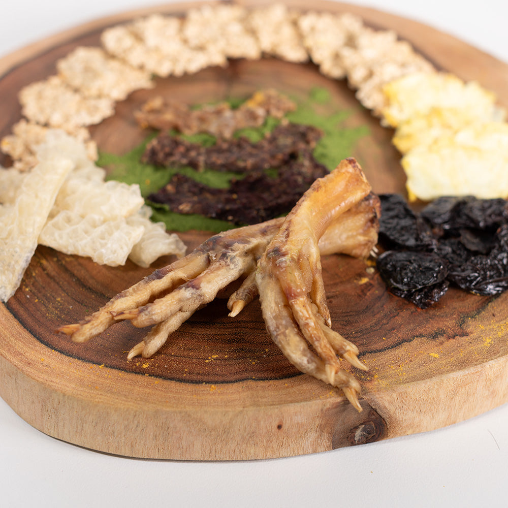 Front view of the barkuterie board with dehydrated chicken feet and other dog treats